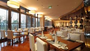 a restaurant with tables and white chairs and large windows at Holiday Inn Nantong Oasis International by IHG in Nantong