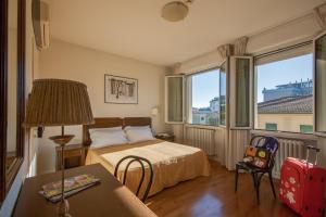 a hotel room with a bed and a table and two windows at Hotel La Pace in Pontedera