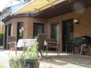 een patio met een tafel en stoelen en een grill bij Ferienwohnung Hammergrund in Mossautal