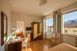 a living room with a table and chairs and two windows at Hotel La Pace in Pontedera