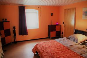 Schlafzimmer mit orangefarbenen Wänden, einem Bett und einem Fenster in der Unterkunft Ferienwohnung Frankenwald in Naila