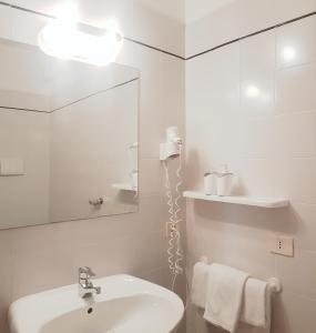 Casa Sandra Bertolini Appartamenti في ناجو توربولي: حمام أبيض مع حوض ومرآة