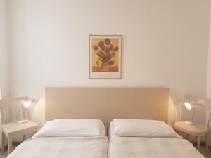 Casa Sandra Bertolini Appartamenti في ناجو توربولي: غرفة نوم بسريرين وصورة على الحائط