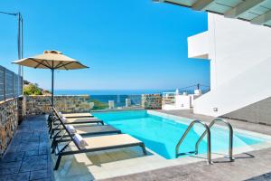 ein Swimmingpool mit Liegestühlen und Sonnenschirm in der Unterkunft Petasos in Plakias