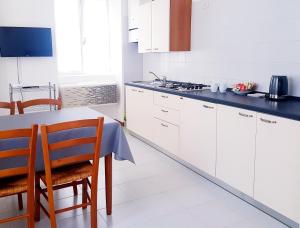 Casa Sandra Bertolini Appartamenti في ناجو توربولي: مطبخ مع دواليب بيضاء وطاولة وكراسي