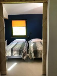 2 camas en una habitación con paredes azules y ventana en BIELICE Chatka Trapera & Co, en Stronie Śląskie