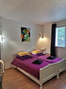 een slaapkamer met een bed met paarse lakens en een raam bij Route de Nieul in Le Girouard