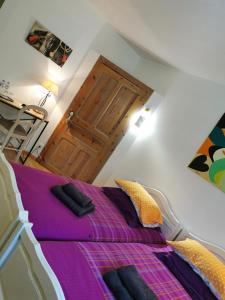 een slaapkamer met een bed met paarse lakens en een houten deur bij Route de Nieul in Le Girouard