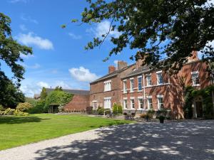 a large red brick building with a grass yard at Singleton Lodge Country House Hotel in Poulton le Fylde