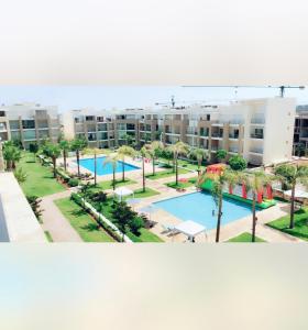 um grande complexo de apartamentos com piscina e palmeiras em Luxury Apartement Near the Beach em Sidi Bouqnadel