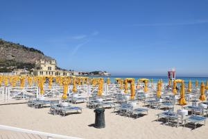 a beach with chairs and yellow umbrellas and the ocean at B&B Ponticello in Palermo