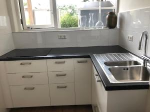 a kitchen with white cabinets and a sink and a window at Savina City Centre Apartment Near Beach, Station and Shops in Zandvoort