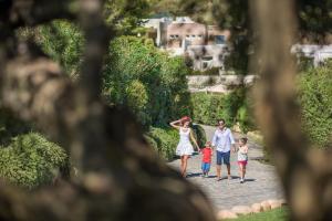 a family walking down a path in a park at Chia Laguna - Hotel Village in Chia