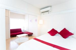 um quarto branco com almofadas vermelhas e um sofá vermelho em Yokkaichi Nishishinchi Hotel em Yokkaichi