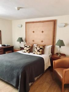 a bedroom with a large bed and a chair at Lensfield Hotel in Cambridge