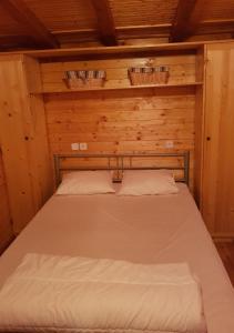 Bett in einem Holzzimmer mit zwei Körben an der Wand in der Unterkunft Camping International 242 Porlezza Italië in Porlezza