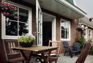 a wooden table on a patio with chairs and flowers at Slapen bij Jesse in Broek in Waterland