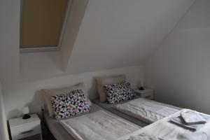a small room with two beds and pillows at Sziget Vendégház in Szigliget