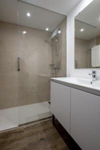 een witte badkamer met een douche en een wastafel bij Aparthotel las Dunas in Chiclana de la Frontera