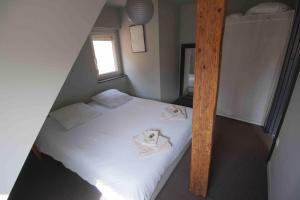 una piccola camera da letto con un letto con lenzuola bianche di La Cour de Berthe Est a Colmar