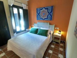 een slaapkamer met een wit bed met groene kussens bij La Esperanza in Alcalá del Valle