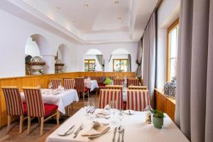 a restaurant with white tables and chairs and windows at Hotel Der Schmittenhof in Zell am See