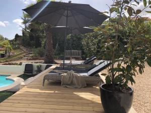 un patio con sombrilla, sillas y piscina en Casa Sereno en Benagil