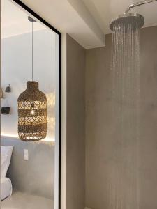 La salle de bains est pourvue d'une douche et d'un lustre. dans l'établissement Andros Utopia, à Batsi