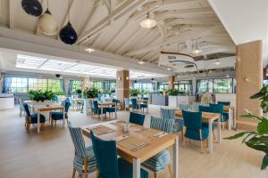 a restaurant with wooden tables and blue chairs at Valamar Tamaris Resort in Poreč