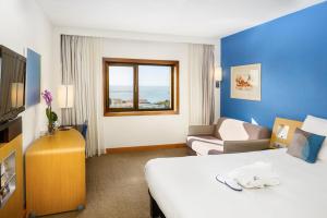 a hotel room with a bed and a couch at Novotel Porto Gaia in Vila Nova de Gaia