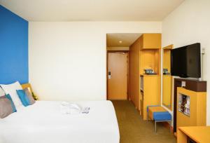 a hotel room with a bed and a flat screen tv at Novotel Porto Gaia in Vila Nova de Gaia