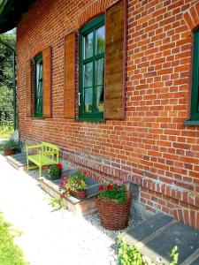 a brick building with a bench and some flowers at Gajówka in Węgorzewo