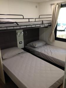 two bunk beds in a room with a window at Casa Mobile - Spiaggia e Mare Holiday Park in Porto Garibaldi