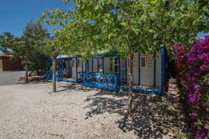 una pequeña casa azul con árboles y flores púrpuras en Camping Bon Sol en El Campello
