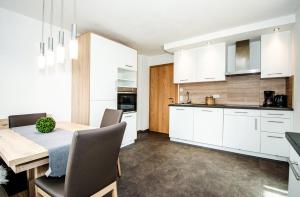 a kitchen with white cabinets and a wooden table at Apartment Mayerhofer in Mittersill +26 photos
