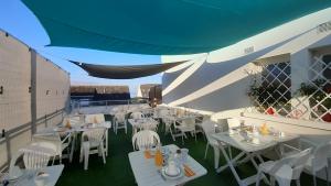 a restaurant with white tables and chairs on a balcony at Hôtel Ker-Noyal Quiberon Plage in Quiberon