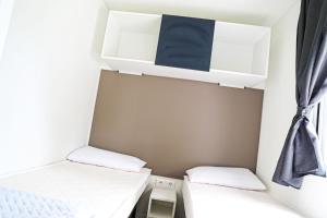 a small bedroom with two beds and a window at Camping Rose in Dormelletto