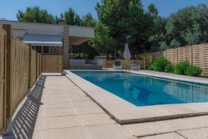 a swimming pool in a backyard with a wooden fence at Chalet Bon Sol in El Campello