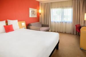 a hotel room with a large bed and a chair at Novotel Porto Gaia in Vila Nova de Gaia