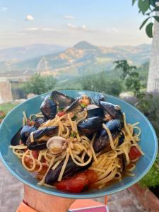 a person holding a plate of pasta and mussels at Il Monte Farmhouse in Torricella Peligna