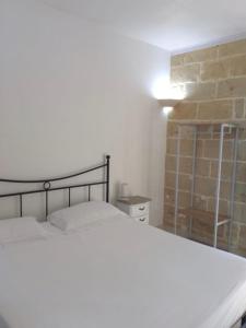 1 dormitorio con cama y pared de ladrillo en Le stanze di Ray, en Borgagne