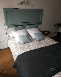 a bed with a green headboard and two pillows at Chez Anne in Fécamp