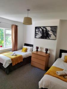 a bedroom with two beds and a dresser and a window at Perry Road, beautiful large house available for Guests and Contractors Parking wifi in Nottingham