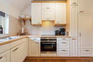 una cocina blanca con armarios blancos y fregadero en Vakantiehuis Villa 32, en Heel