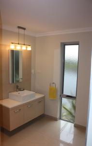 baño con lavabo, espejo y ventana en Harbour Lookout en Strahan