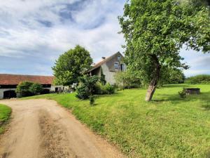 a dirt road in front of a house with a tree at Ekskluzywny apartament na warmińskiej wsi Tłokowo-Mikułowo in Jeziorany