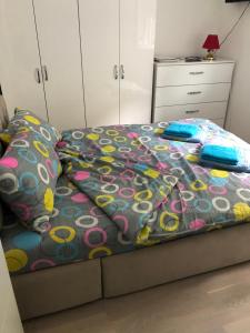 um quarto com uma cama com um edredão colorido e almofadas em Sunce em Kruševac