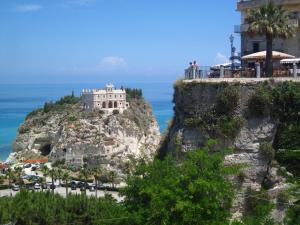 a building on top of a mountain next to the ocean at Appartamento Miele in Zambrone