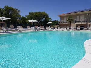 a large swimming pool with chairs and umbrellas at Appartamento Miele in Zambrone