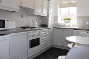 eine Küche mit weißen Schränken und einem Herd mit Backofen in der Unterkunft Riverside Apartment in Ayr